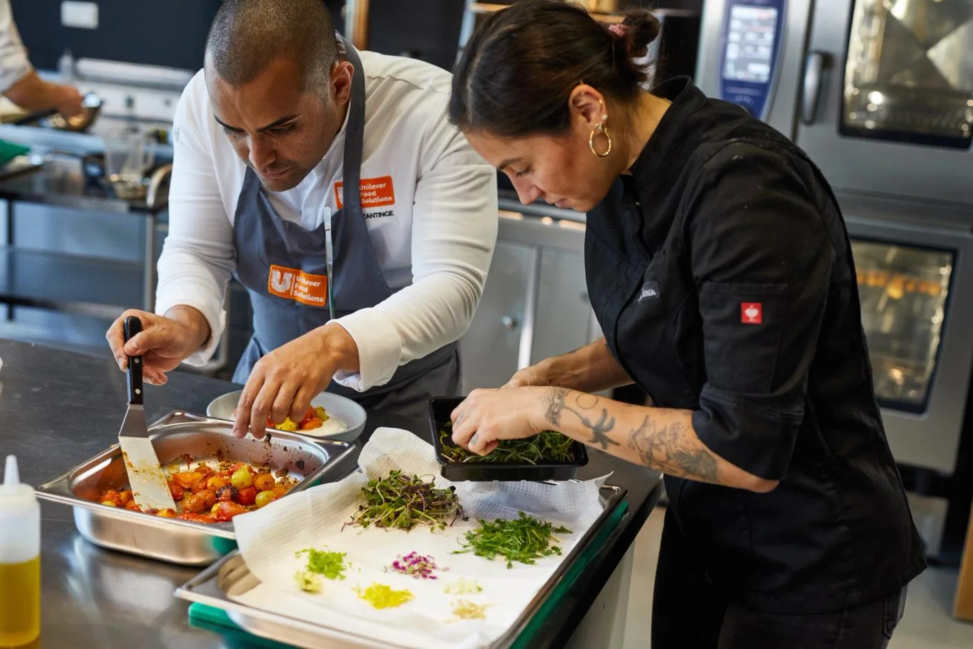 Two culinary professionals preparing food in a professional kitchen